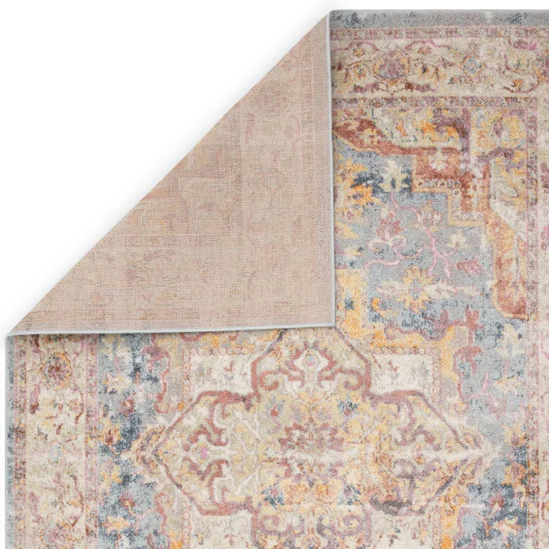 Vintage pattern area rug with faded pastel colors and turned corner showing rug backing