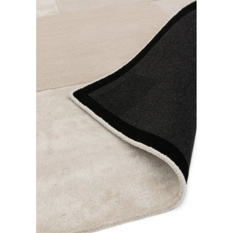 Beige area rug with a corner flipped to show black non-slip backing