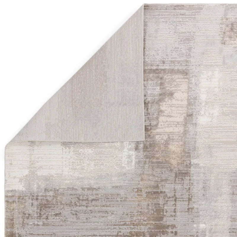 Beige and grey abstract area rug with folded corner showing backing texture