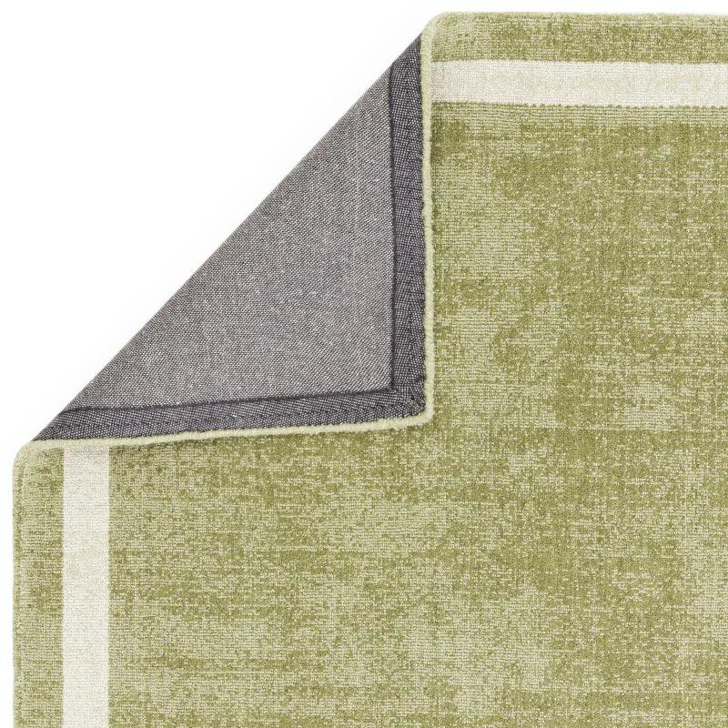 Green area rug with cream border, corner folded to show textured underside