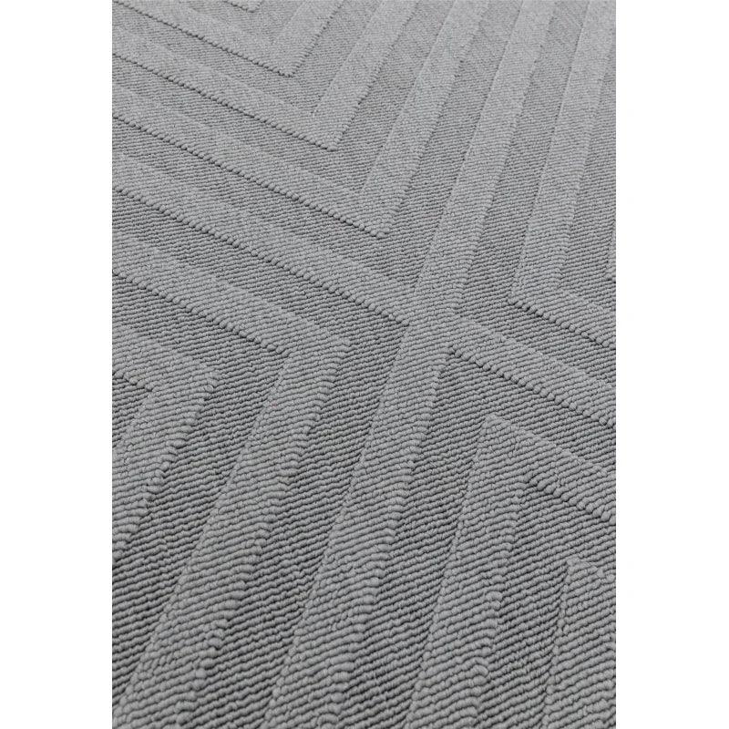 Grey textured rug with geometric chevron pattern, close-up view of soft woven surface