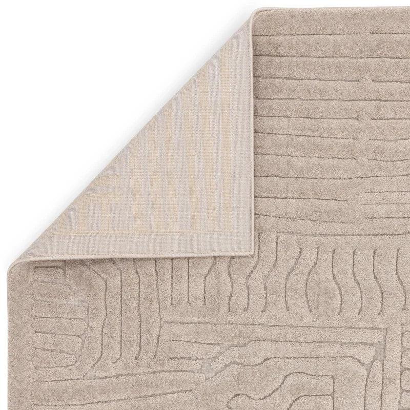 Beige textured area rug with abstract linear pattern and corner flipped to show backing