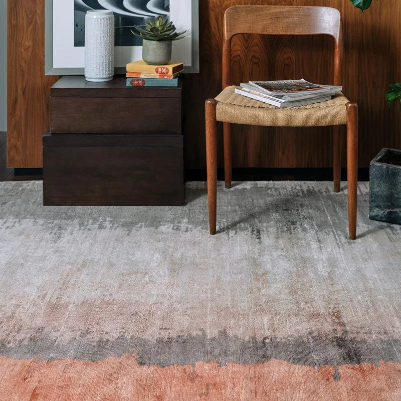 Modern area rug with grey and rust tones beneath a wooden chair and side table