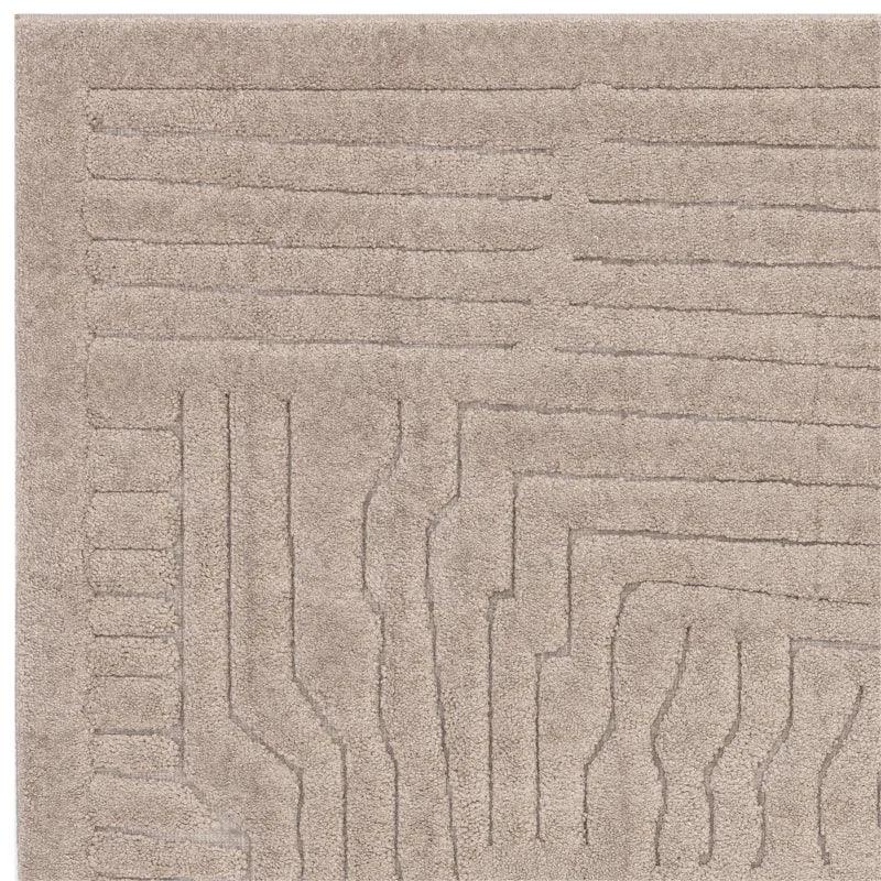 Beige area rug with embossed linear geometric pattern, close-up of corner texture and detail