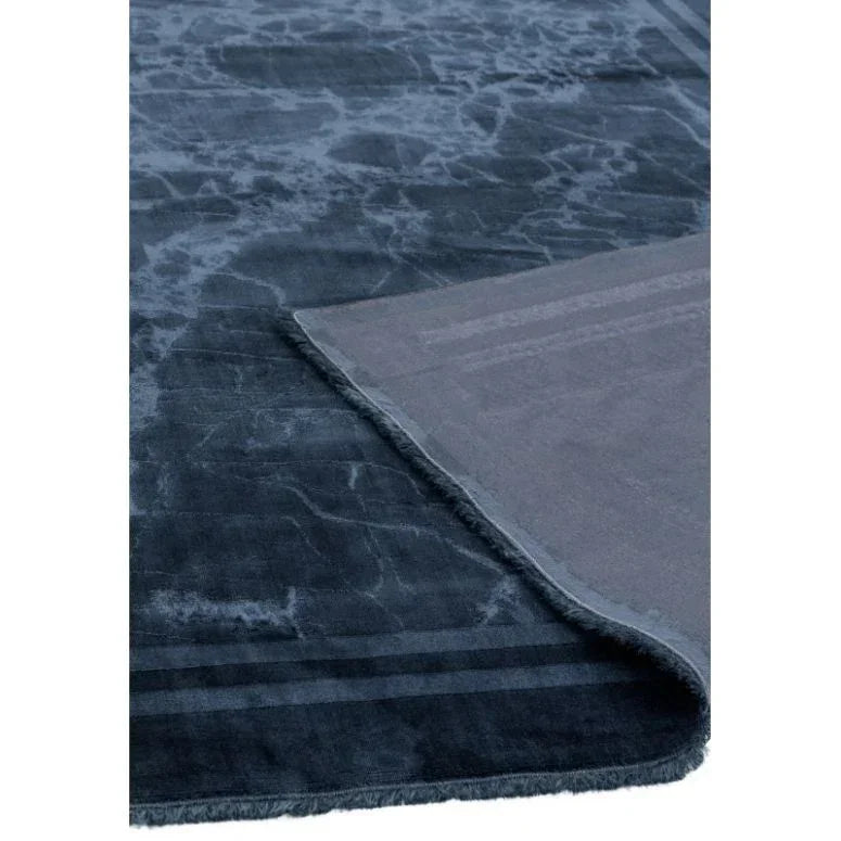 Dark blue textured area rug with corner folded to show soft underside