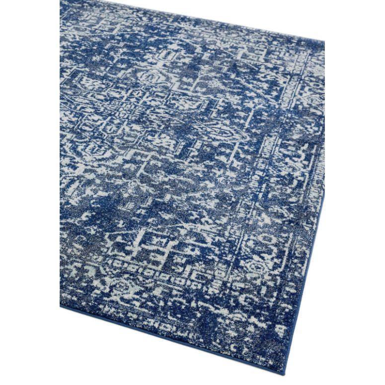 Blue patterned area rug with distressed white detail, corner view