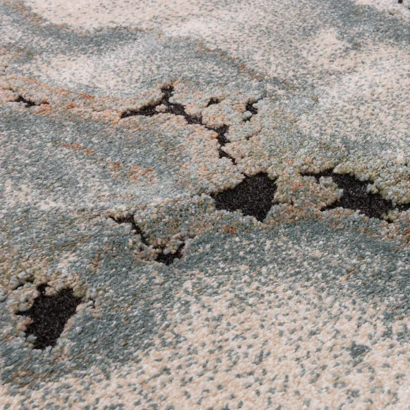 Close up of textured area rug with abstract blue, cream, and black pattern