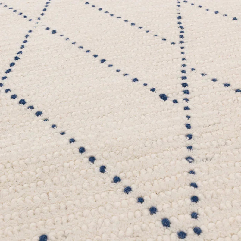 Closeup of cream and blue wool rug with dotted geometric pattern