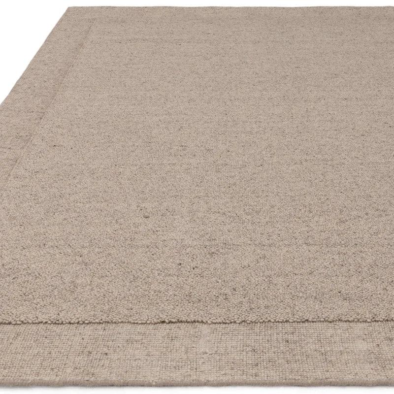 Beige wool rug with textured weave and wide border detail, shown from corner angle