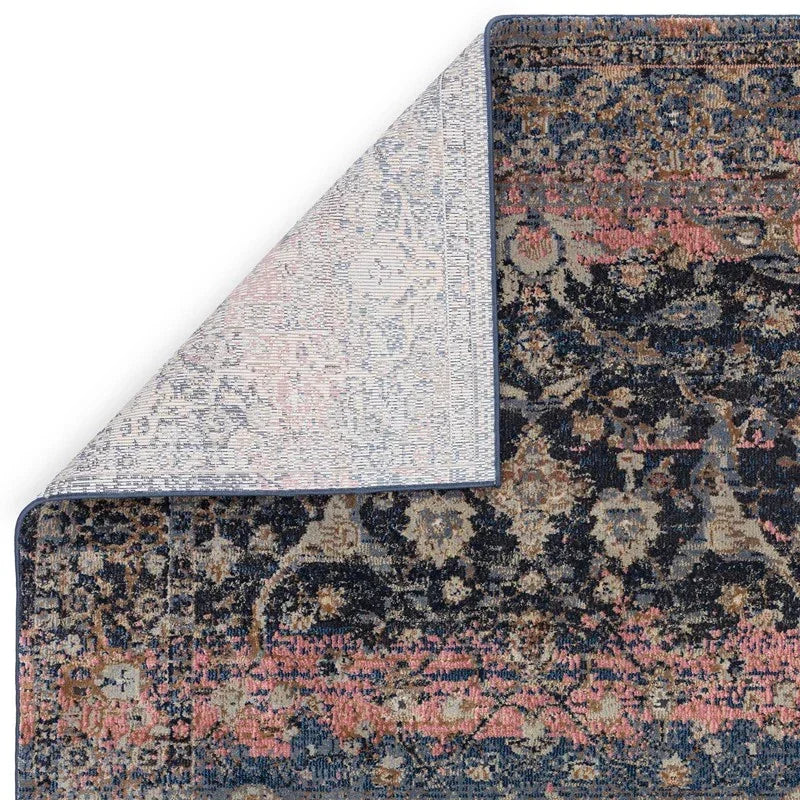 Corner of navy and pink patterned area rug showing detailed weaving and finished edge