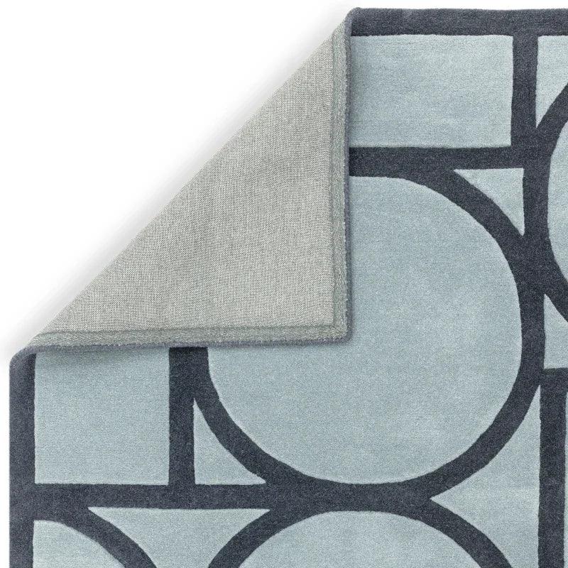 Light blue geometric rug with contrasting dark blue circle and line pattern, corner folded