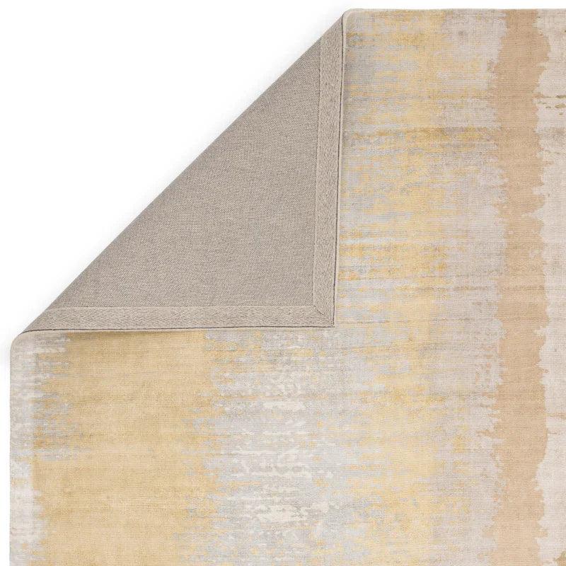 Beige and grey area rug corner with subtle textured pattern, backing partially visible