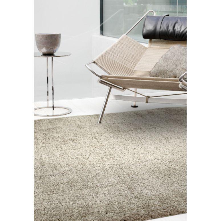 Beige shaggy rug on living room floor beside modern chair and chrome side table