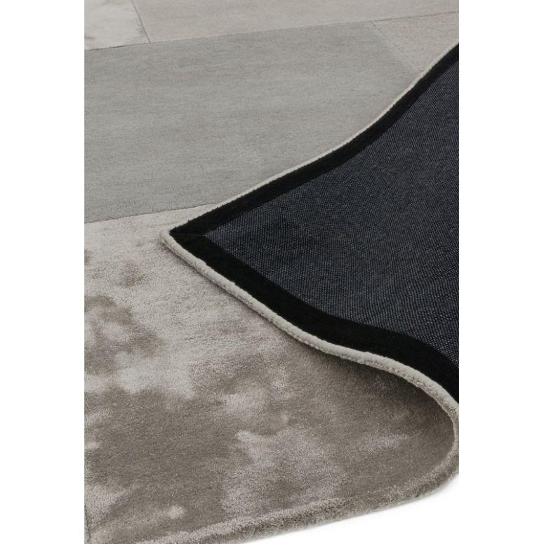 Close up of grey area rug corner showing soft pile and black non-slip backing