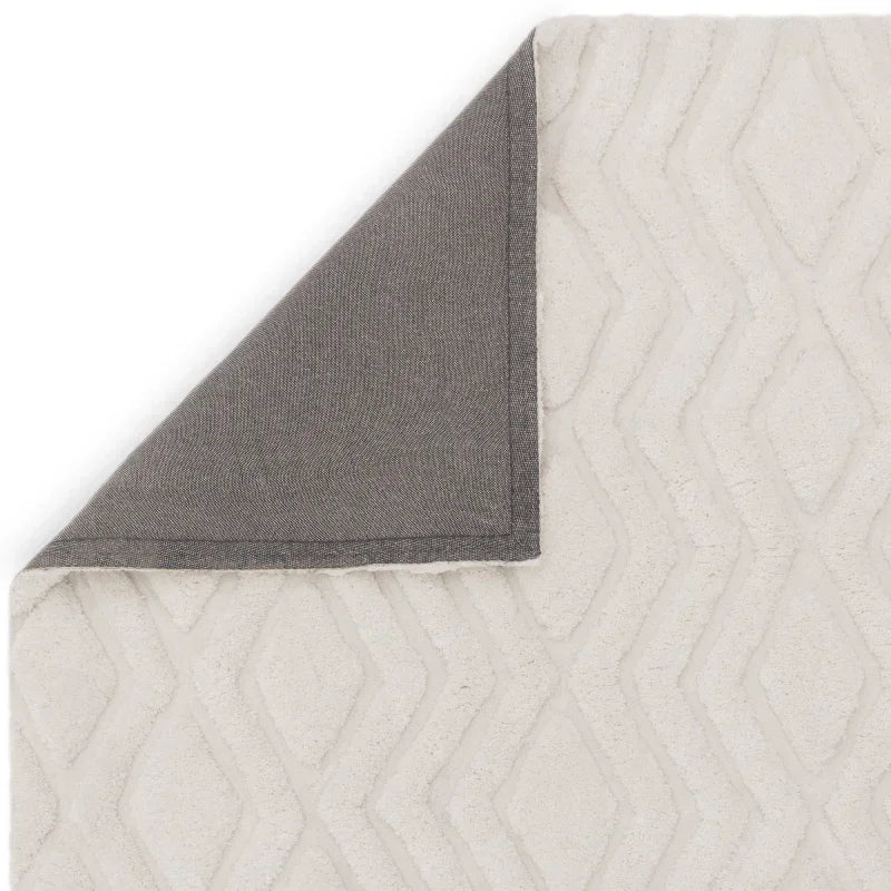 Cream geometric rug with textured diamond pattern and corner folded to show grey backing