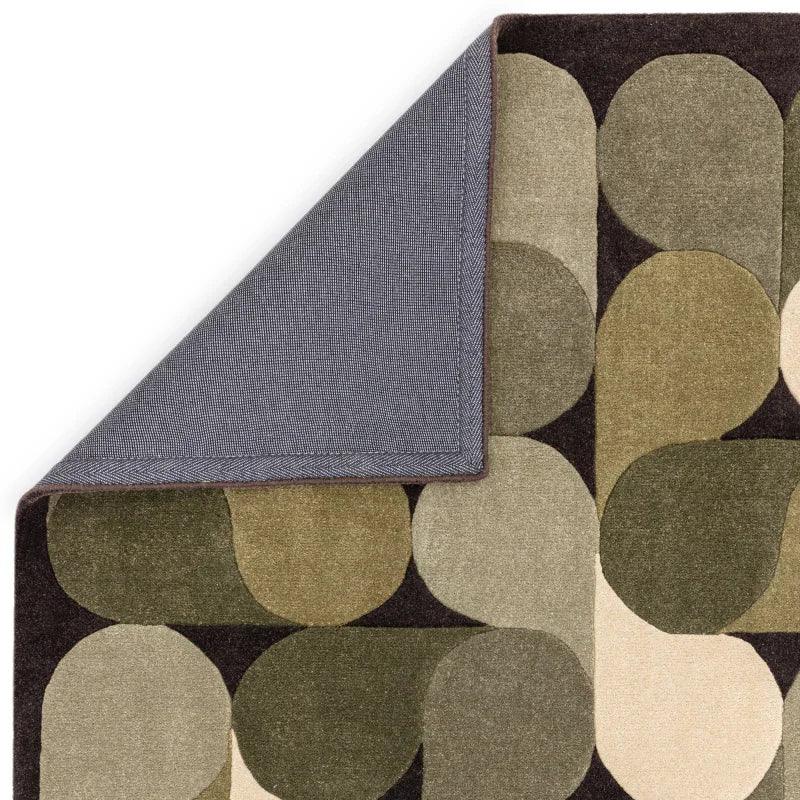 Geometric patterned area rug in green and beige tones with corner turned to show backing