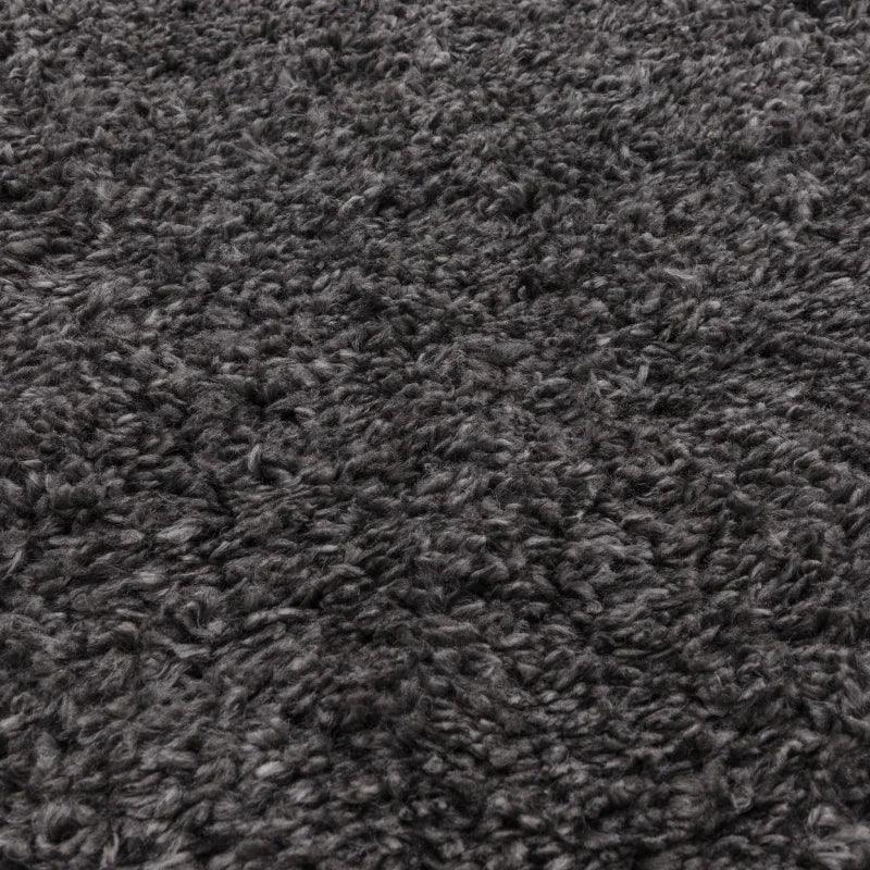 Closeup of dark grey shaggy rug texture with dense pile