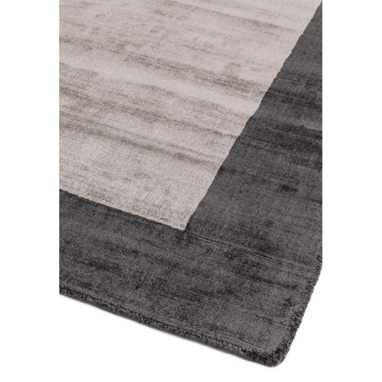 Grey and light beige area rug with contrasting border, close-up of textured fabric