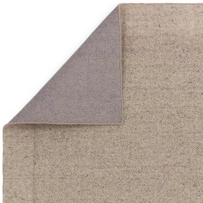 Beige textured rug with visible corner showing grey fabric backing