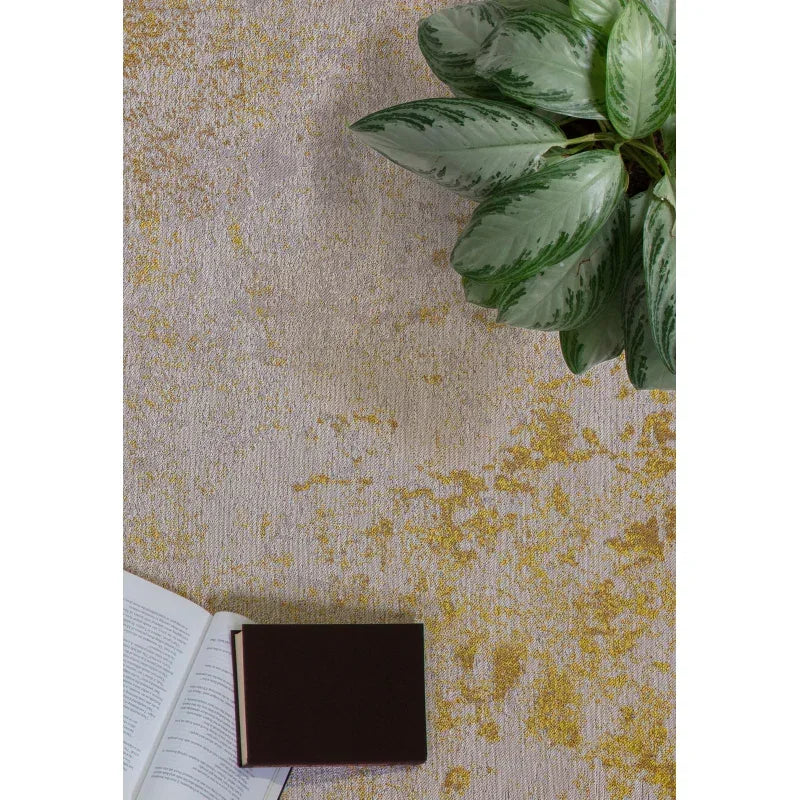 Modern gold textured rug with open book and green houseplant for living room decor