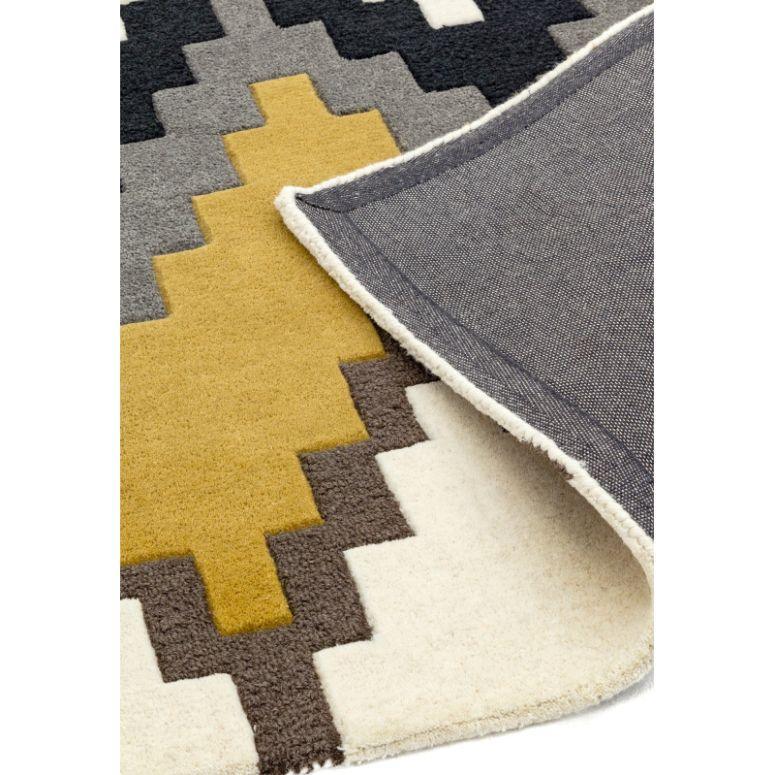 Geometric patterned rug in yellow, grey, cream and black with corner folded to show backing