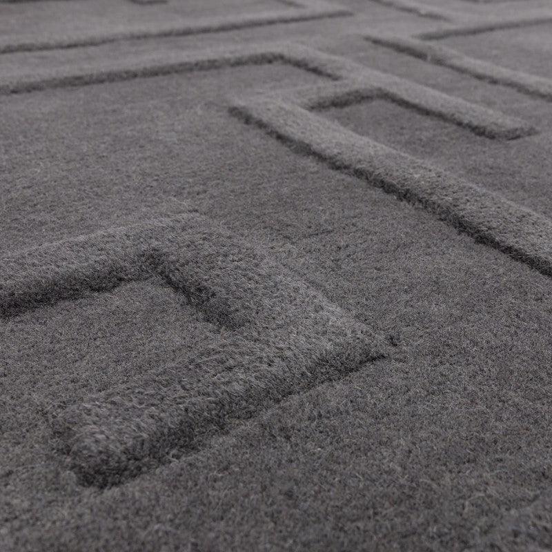 Closeup of grey geometric wool rug with raised square pattern texture