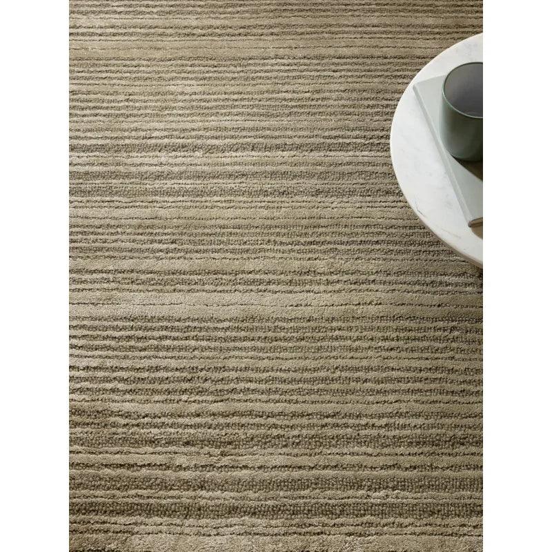 Beige textured area rug with horizontal stripe pattern and round coffee table corner
