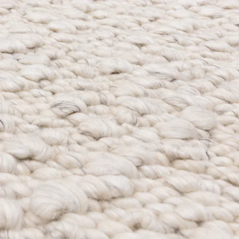 Close-up of cream wool rug texture with chunky handwoven loops