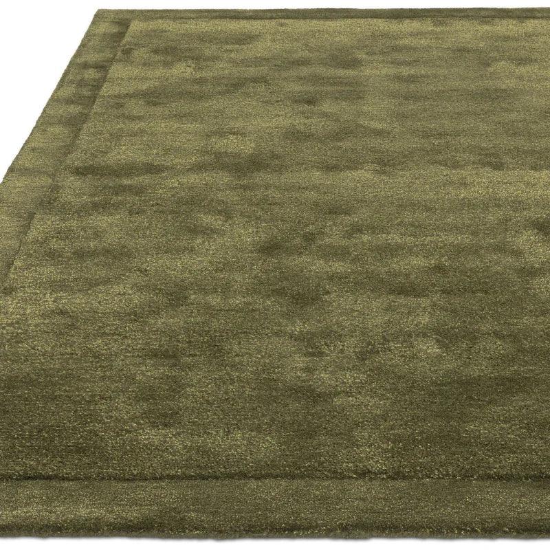 Olive green area rug with subtle border detail and soft texture, shown from angled view