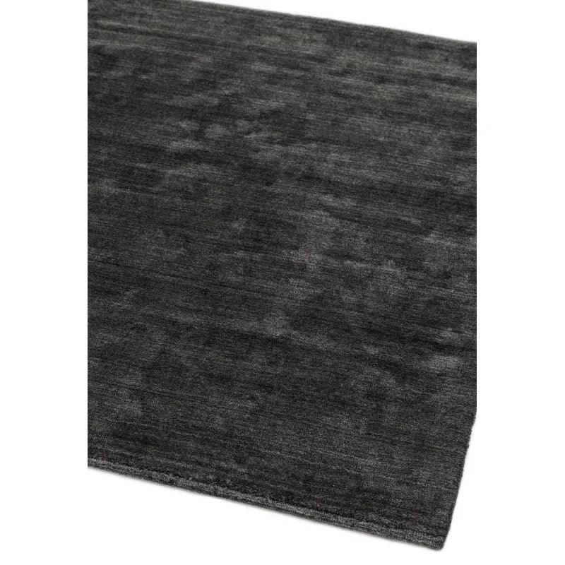 Dark grey area rug with subtle textured pattern, corner view on white background