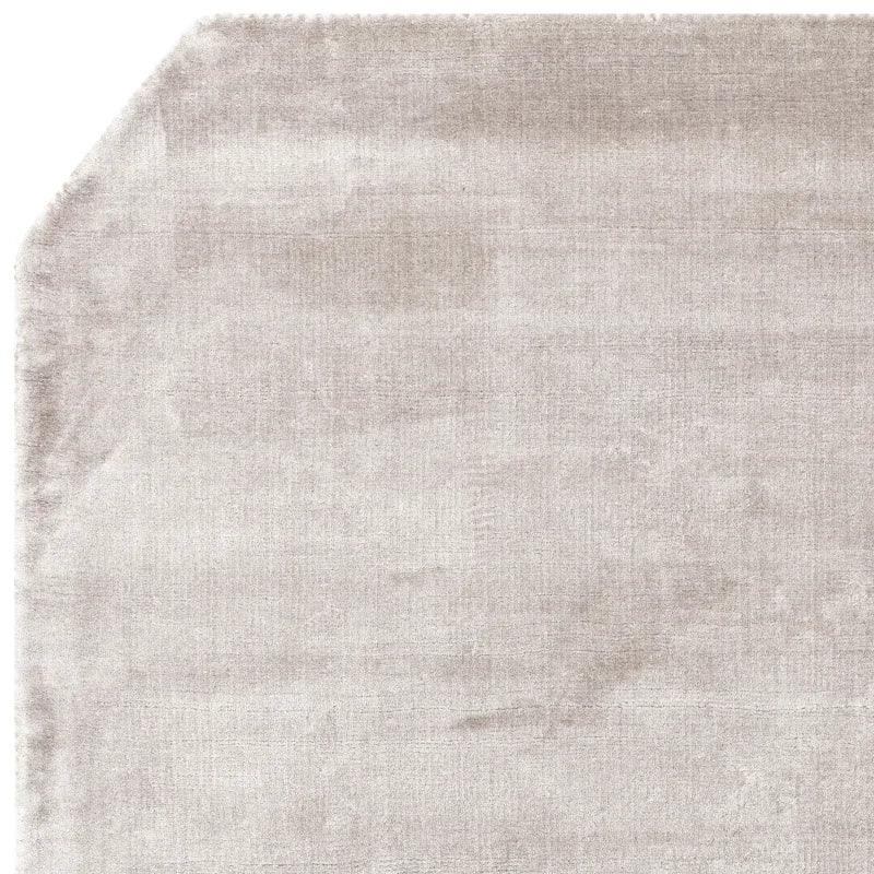 Light grey area rug with angled corner and subtle textured pattern