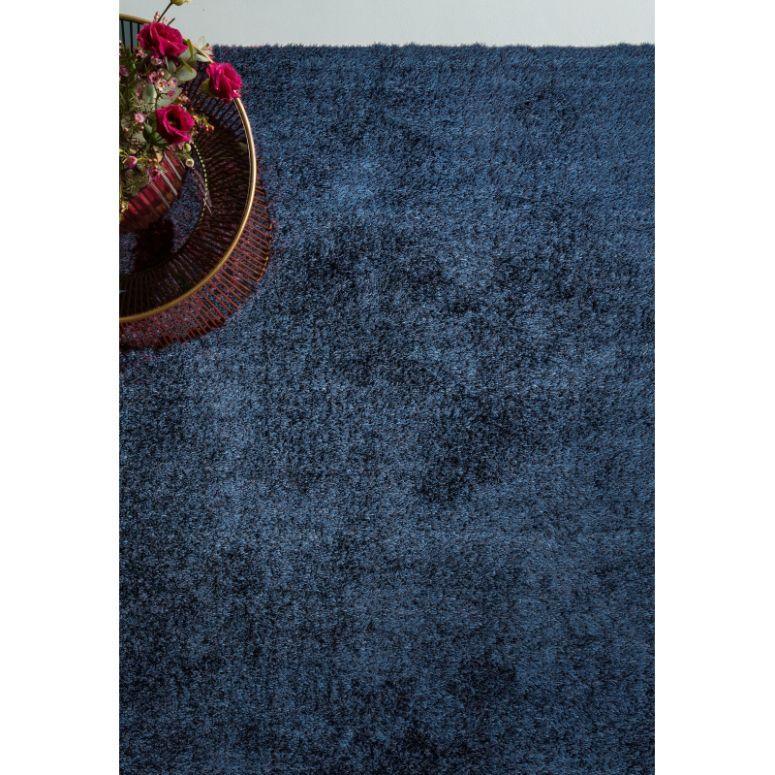 Plush blue shaggy rug with textured pile and modern gold side table with flowers