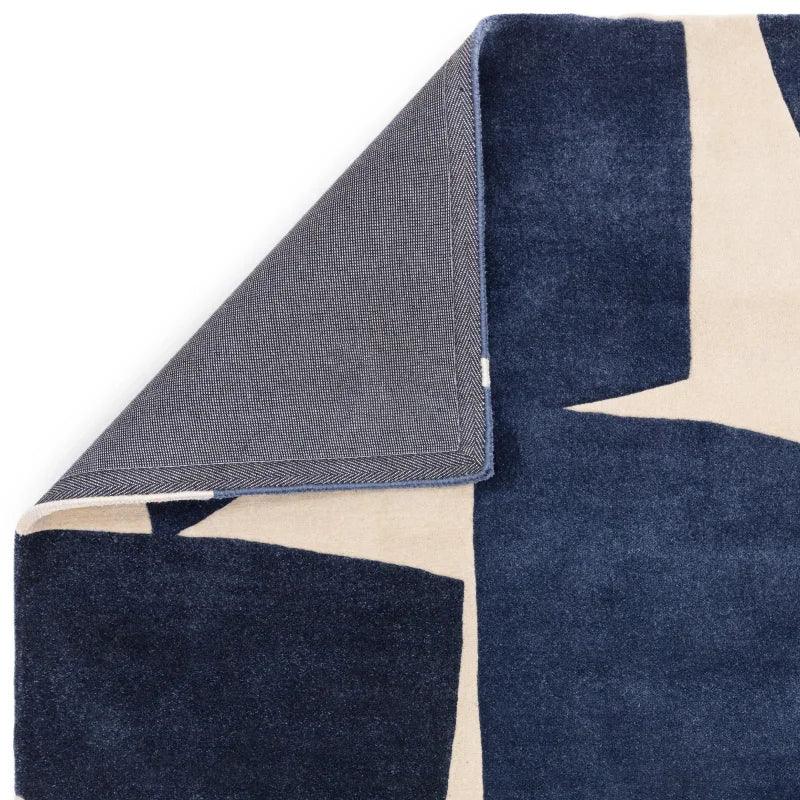 Modern abstract area rug with navy and cream geometric pattern, corner flipped to show backing
