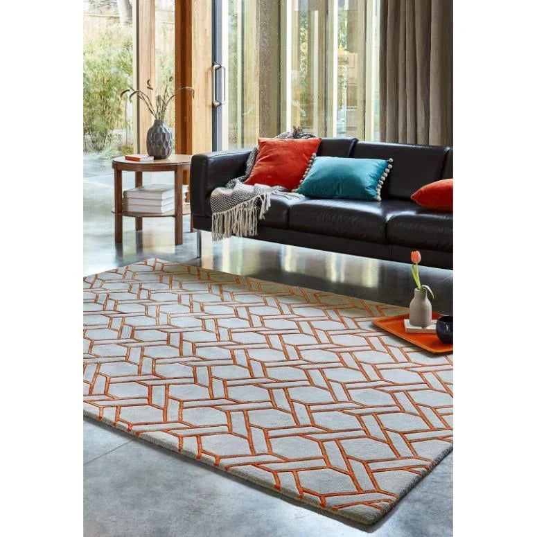 Geometric pattern rug with orange accents in modern living room with black sofa