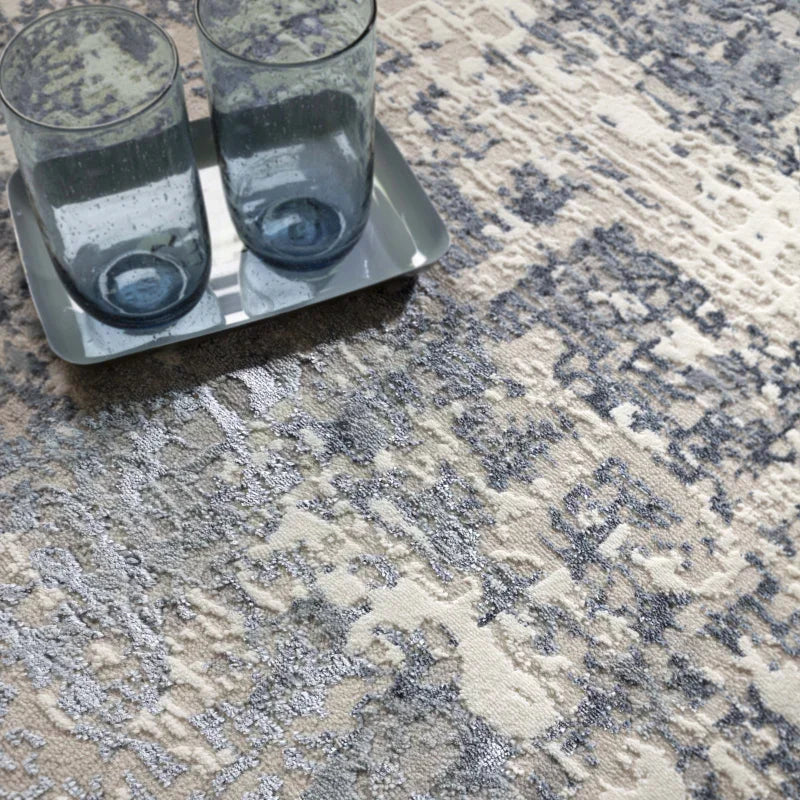 Modern abstract area rug in grey and cream with close-up of two glass tumblers on tray