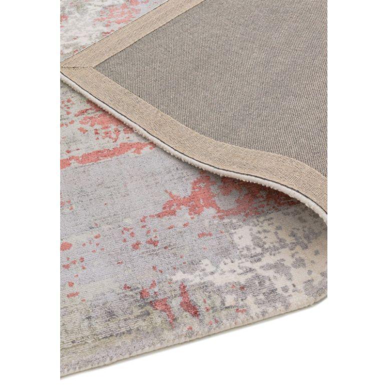 Modern area rug with abstract pink and grey pattern, corner folded to show backing