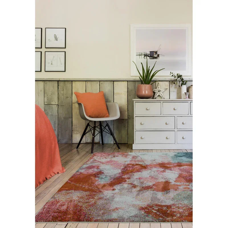 Abstract orange and grey area rug in a modern bedroom with white chest and accent chair