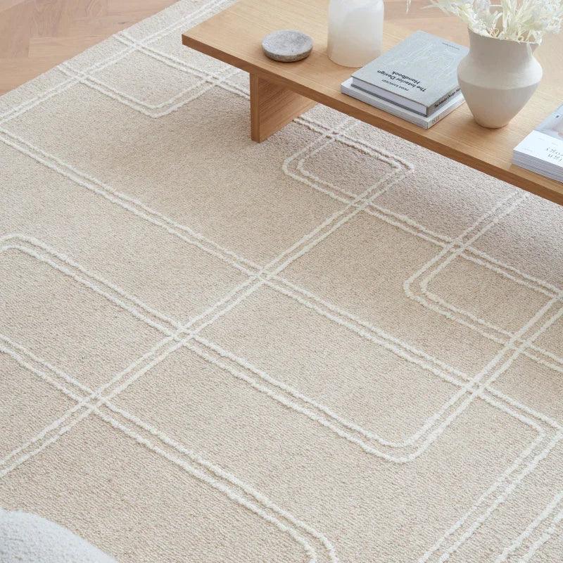 Beige geometric rug under wooden coffee table with books and vase in modern living room