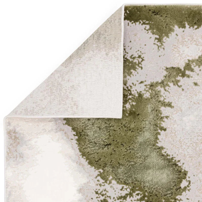 Green and beige abstract area rug corner with visible backing