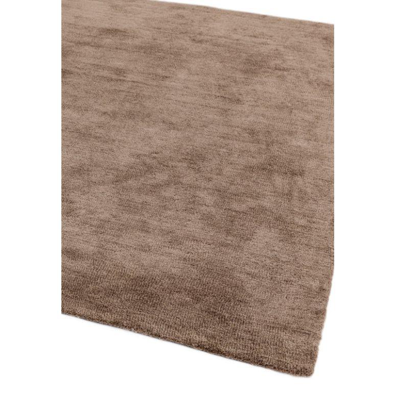 Brown area rug with soft textured surface and square corner, close-up view