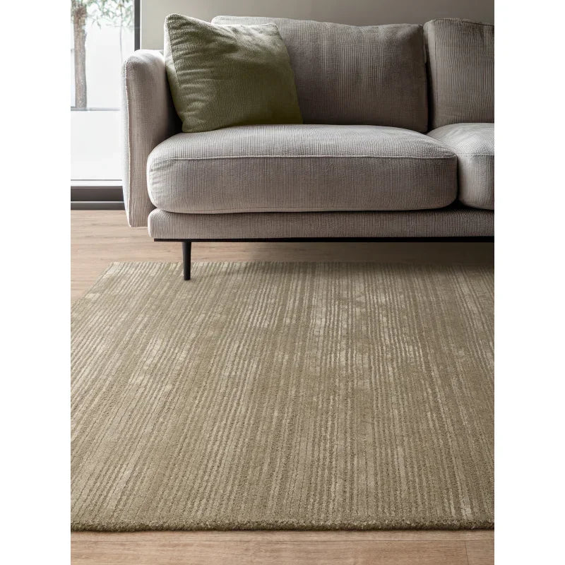 Beige textured area rug beneath modern grey sofa with green cushion in living room setting
