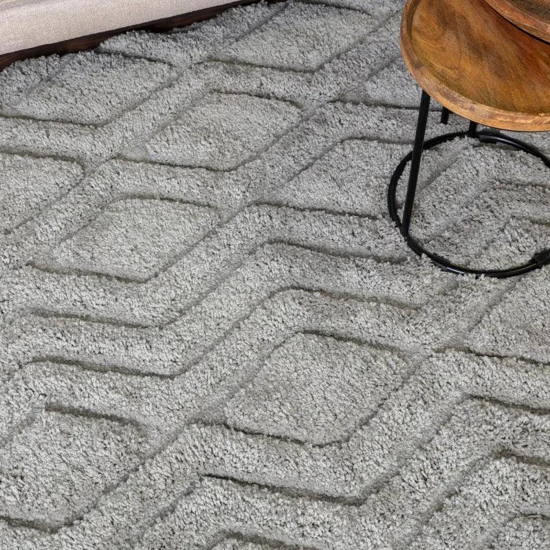 Grey geometric pattern rug with textured detail beneath wooden side table