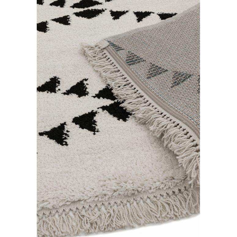 Black and white geometric rug with triangle pattern and fringed edge, close-up view