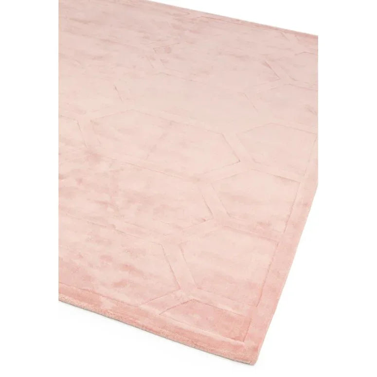 Blush pink area rug with subtle geometric pattern and soft texture, shown from an angled view