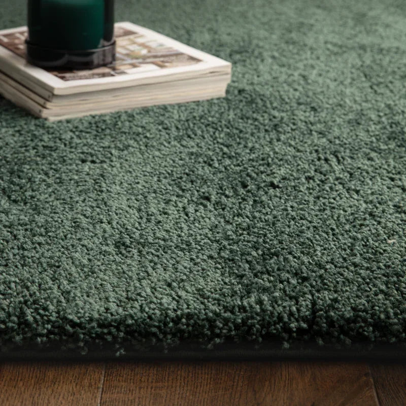 Green shaggy rug on wooden floor with close-up of soft pile and decorative candle
