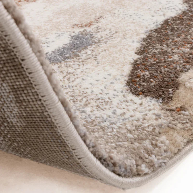 Close-up of beige and brown patterned area rug with textured pile and bound edge