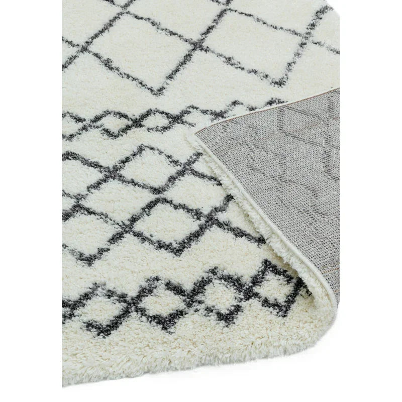 Cream shaggy rug with black diamond pattern and visible textured backing detail