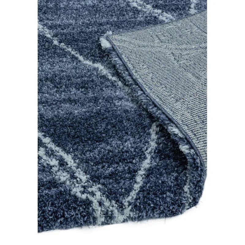 Blue shaggy rug with white geometric lines, close-up of corner and textured pile