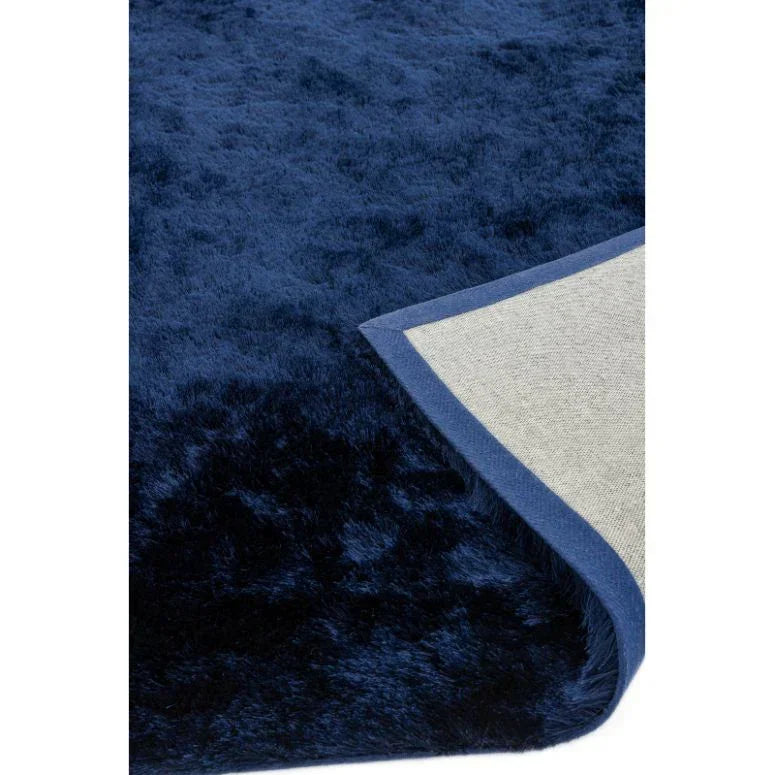 Navy blue faux fur rug with fabric backing, close-up of corner detail