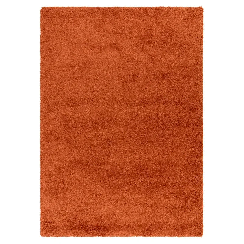 Rectangular orange shaggy rug with soft textured pile on white background